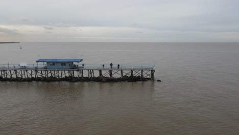 Aerial-view-of-people-on-long-pier-over-water-in-the-vast-endless-ocean