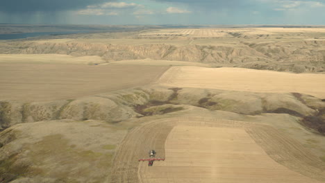 A-Seeding-Tractor-At-Work-At-The-Sweeping-Terrain-Of-Farmland-In-Saskatchewan,-Canada