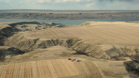 Seeding-in-Saskatchewan,-Canada-with-Lake-Diefenbaker-in-background,-wide-aerial