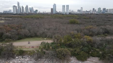 People-on-bicycle-riding-on-path-in-front-of-city-skyline-in-Buenos-Aires-at-cloudy-day