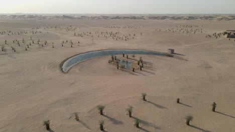 Drone-view-of-the-Moon-Lake-in-Dubai,-Moon-Shape-Lake-is-in-the-middle-of-Al-Qudra-desert,-surrounded-by-golden-sand-dunes-in-the-United-Arab-Emirates