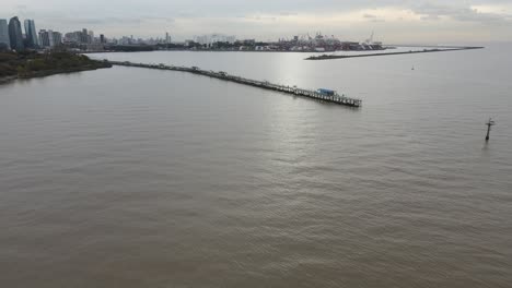 Aerial-backwards-shot-of-pier-and-port-next-to-skyline-of-Buenos-Aires-during-cloudy-day,Argentina