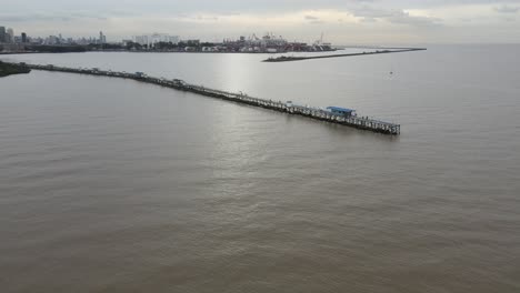 Aerial-view-of-pier-extending-from-land-out-over-water-in-the-vast-endless-ocean