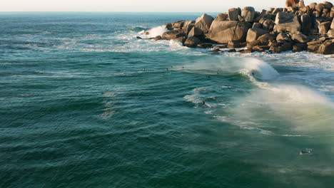 Un-Grupo-De-Surfistas-Esperando-La-Próxima-Ola-Mientras-Disfrutan-De-La-Puesta-De-Sol-En-Llandudno,-Kaapstad
