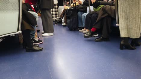 Punto-De-Vista-A-Los-Pies-Desde-El-Interior-Del-Tren-Subterráneo-En-Tokio,-Japón,-Con-Muchos-Pasajeros-Dentro