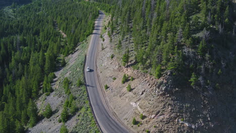 Coche-Blanco-Conduciendo-Por-Una-Carretera-A-Través-De-Un-Bosque-Montañoso-De-Colorado