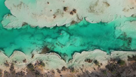 Man-bathing-in-hot-spring,-river-rapids-of-Bacalar-in-Mexico,-4K-aerial-top-down