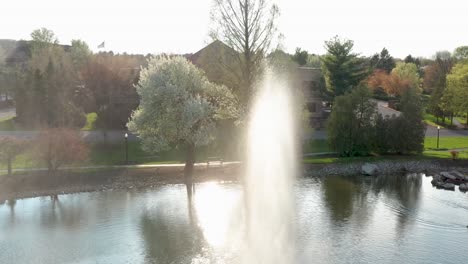 Water-fountain-spray-and-wind-blow-into-aerial-drone-shot-under-beautiful-light