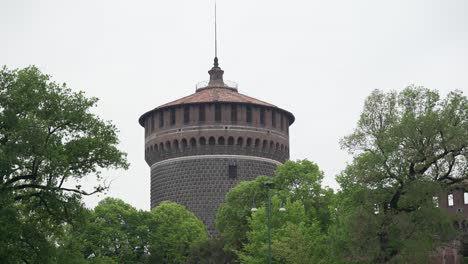 Focus-on-Sforzesco-castle-tower-surrounded-by-trees-of-its-garden