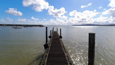 Shimmering-ocean-blue-sky-tranquillity-time-lapse-wooden-jetty-marine-coastline-view