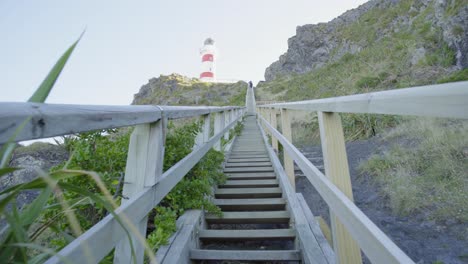 Perspective-shot-walking-up-the-steep-wooden-stairs-towards-a-lighthouse