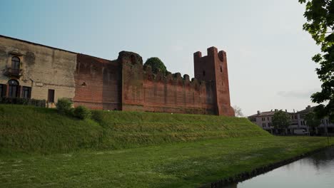 Seitlicher-Statischer-Blick-Auf-Die-Mauern-Der-Burg-Castelfranco-Veneto,-Umgeben-Von-Rasen-Und-Wassergraben