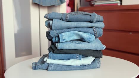 Pila-De-Jeans-Vintage-En-Una-Mesa-Blanca