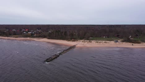 Toma-Aérea-De-Drones-Del-Rompeolas-En-El-Embarcadero-Junto-Al-Mar-Cerca-De-La-Playa-De-Tuuja,-Letonia