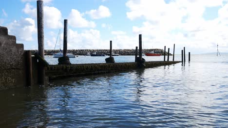 Weathered-wooden-harbour-dock-walkway-on-sunny-Conwy-North-Wales-peaceful-sea-tide