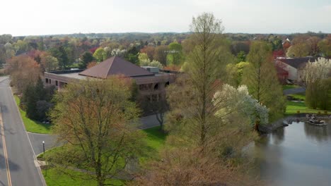 Aerial-establishing-shot-of-business-office-building-set-among-blooming-trees-in-suburban-park-in-United-States,-USA