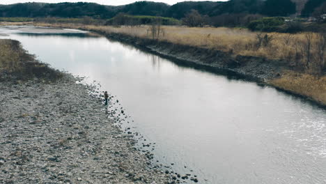 El-Hombre-Se-Para-En-Las-Rocas-Mientras-Pesca-En-El-Río-Durante-El-Día-En-Tokio,-Japón