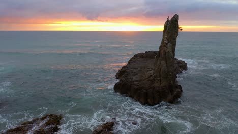Tilt-up-shot-Of-Cathedral-Rocks-and-Swirling-Ocean-With-Dramatic-Sunset-Sky-At-Backdrop-In-New-South-Wales,-Australia---Aerial-Shot