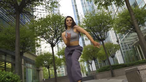 Urban-hip-hop-street-dancer-with-joggers-sports-bra-and-trainers-is-moving-her-body-like-a-pro-various-mixture-of-styles-freestyling-outdoor-on-street-in-city