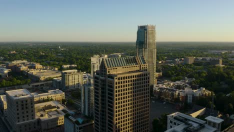 Birds-Eye-Aerial-View-of-Skyscraper-Buildings-in-Green-City-at-Sunrise