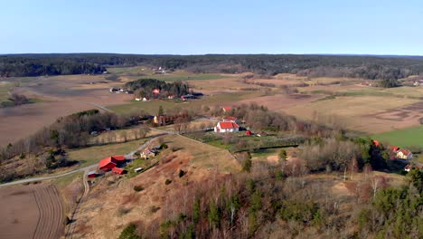 Aerial-Shot-Of-Traditional-Rural-Church-In-Sweden-Surrounded-By-Agricultural-Farm-Land-Landscape