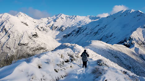 Rear-shot-of-mountaineer-hiking-on-top-of-snowy-mountains-at-Kepler-Track-in-New-Zealand