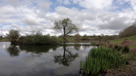 A-cloudy-sky-moving-across-the-countryside-surrounding-a-small-Fly-Fishing-pool-on-a-windy-day-in-Worcestershire,-England
