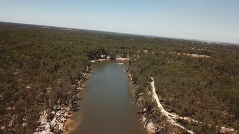 Drone-aerial-over-a-muddy-river-in-Australia-camping-slow-boat-going-past