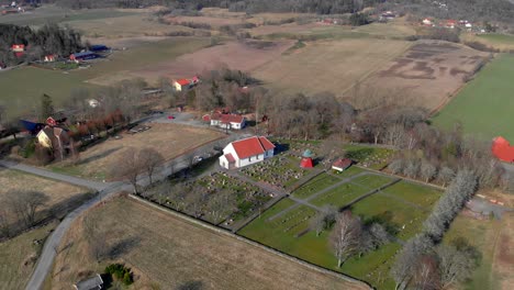 Aerial-Shot-Of-Bergums-Church-And-Cemetery,-Traditional-Rural-Chapel-And-Village-In-Sweden