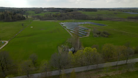 Toma-De-Drones-De-4k-De-Autos-Conduciendo-En-Un-Camino-Rural-Al-Lado-De-Una-Granja-De-Paneles-Solares-En-Campos-De-Campo-En-Polonia