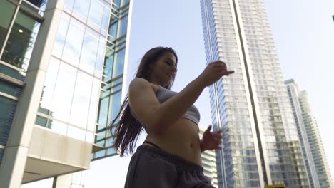 Positive-dancer-with-joggers-and-short-top-body-wave-her-body-dancing-mix-of-hip-hop-styles-twerking-surrounded-with-big-towers-and-buildings-city-vibe-movie-scenery-slow-motion