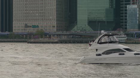 A-small-yacht-and-jet-ski-make-their-way-up-New-York-bay-as-traffic-traverses-the-FDR-drive-in-Manhattan-in-the-backdrop