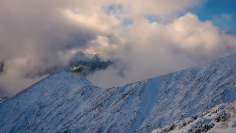 Spectacular-panning-shot-showing-snowy-peaks-of-mountains-covered-by-clouds-and-fog
