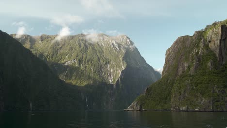 Scenic-landscape-shot-of-huge-mountain-faces-in-the-sun-with-a-valley-of-water-going-between-them-in-New-Zealand's-Milford-sound