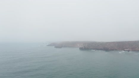 Coastal-Cliffs-In-Serene-Ocean-During-Hazy-Morning-In-Portugal