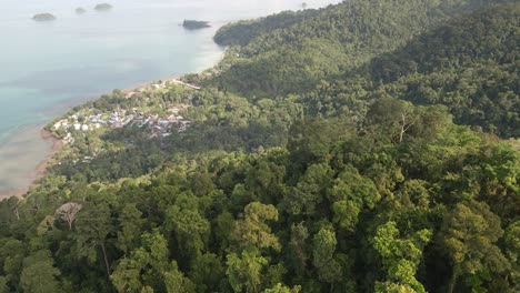 backwards-Aerial-shot-of-dense-tropical-forest-with-ocean-and-islands,-Koh-Chang