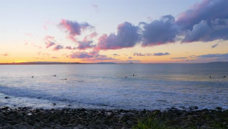 Surfer,-Die-Während-Des-Sonnenuntergangs-Im-Noosa-nationalpark-In-Queensland,-Australien,-Auf-Ihren-Surfbrettern-Am-Strand-Schweben