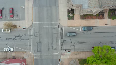 Top-down-aerial-of-car-driving-through-intersection-on-street-in-city-in-USA
