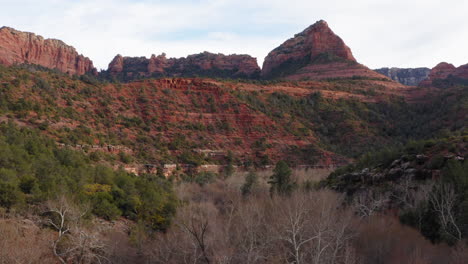 Aerial:-mountain-valley-with-dry-tree-forest-at-Sedona,-Arizona---drone-flying-forward-shot