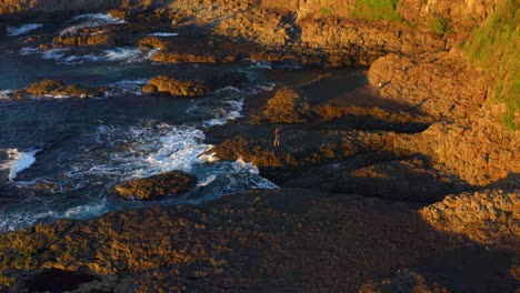 Person-Standing-On-Volcanic-Outcrops-On-Rocky-Coast-At-Cathedral-Rocks-Near-Jones-Beach-in-Kiama-Downs,-NSW-Australia