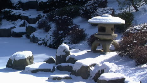 Linterna-Japonesa-Cubierta-De-Nieve-Junto-A-Un-Estanque