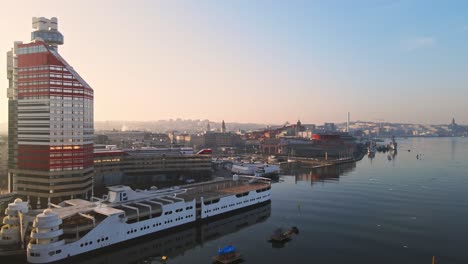 Tram-Travelling-At-Gotaalvbron-Bridge-With-P-Arken-Ship-On-Harbour-Beside-Lilla-Bommen-Building-At-Sunrise-In-Gothenburg,-Sweden