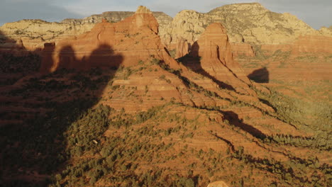 Aerial:-wild-red-rock-mountain-valley-in-sunlight-at-Sedona,-Arizona---establishing-drone-flying-forward-shot