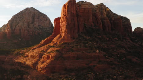 Red-rock-mountain-valley-in-sunlight-at-Sedona,-Arizona---butte-landscape-establishing-drone-shot