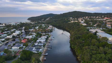 Boat-Sailing-At-Calm-Water-Of-Noosa-River-With-Townscape-Of-Noosa-Heads,-Queensland,-Australia