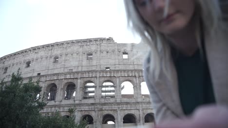 A-blonde-girl-playing-with-her-phone-in-front-of-colloseum
