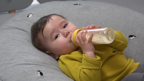 Baby-boy-drinking-formula-milk-holding-the-bottle-in-both-hands