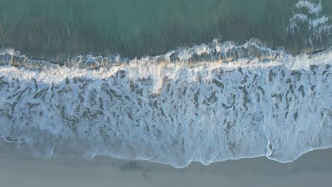 UAE:-Aerial-view-of-waves-breaks-on-the-beach,-Bird's-eye-view-of-ocean-waves-crashing-and-foaming-against-the-empty-shore,-rough-sea-view