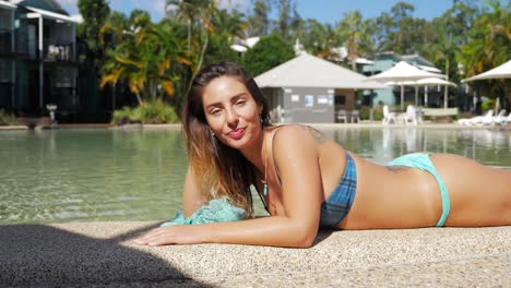 Young-Caucasian-Girl-Smiling-At-Camera-While-Lying-On-Stomach-On-Poolside---Holiday-Trip