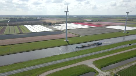 Cargo-ship-moves-through-straight-canal-in-Dutch-countryside-with-windmills